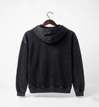 Black hoodie on a hanger against a white background
